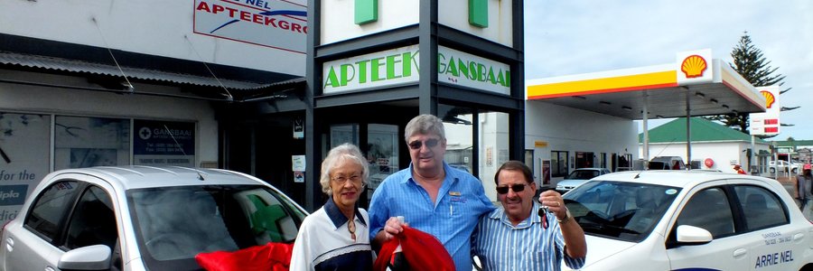 ‘n Dankbare Gerhard Roux (regs) van Franskraal, nadat hy ‘n Toyota Etios 1.5ltr van Arrie Nel Apteekgroep gewen het, met vlnr Angeline Roux (sy eggenote) en Fanie Viljoen (Apteker/Bestuurder: Gansbaai Apteek) by hom voor Gansbaai Apteek